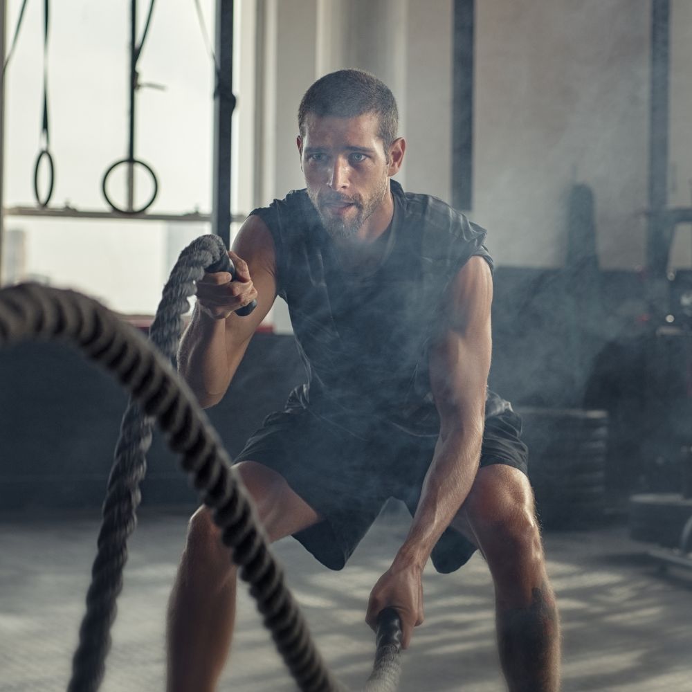 Man exercising with battle ropes in a gym setting